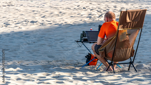 Remote work on the beach with laptop during summer evening