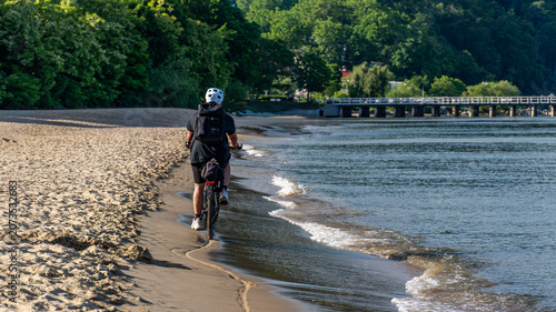 Cyclist riding bicycle along sandy beach coastline