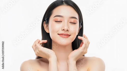 Serene Beauty Unveiled: A young Asian woman with flawless skin and closed eyes gently touches her face, exuding an aura of calm and natural beauty, perhaps a moment of self-care and contemplation.