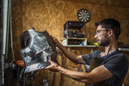Tableau sur toile Artisan armorer creating metal breastplate in workshop