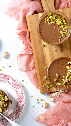 Chocolate mousse pots topped with chopped pistachios served on a wooden board