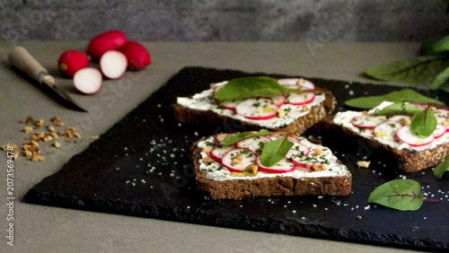 Dark rye bread toasts topped with cream cheese, sliced radishes, and herbs