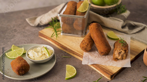 Crispy golden croquettes served with dipping sauce and lime wedges
