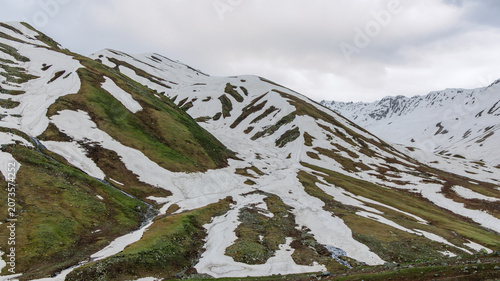 Bild auf Leinwand Diagonal textures of white glacial snowpack retreating to expose untouched earth