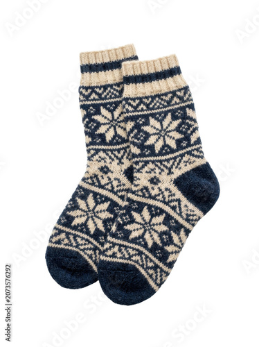A pair of blue and beige patterned winter socks with snowflakes on a white background.