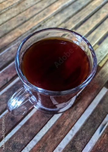 Black cofee in the glass on the wooden table
