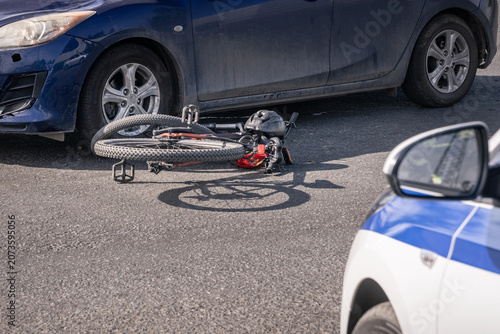 Damaged bicycle after a collision with a car, police car at the accident scene, cyclist accident, road safety, insurance claim and crash investigation
