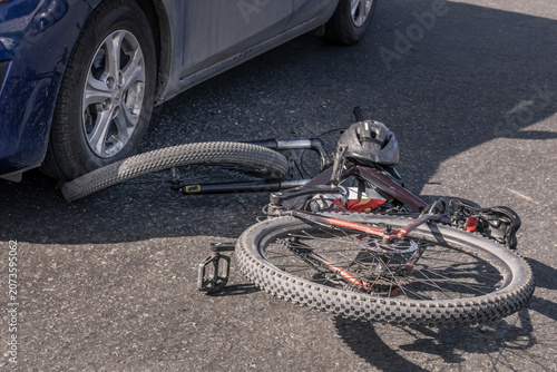 Bicycle accident after a collision with a car, damaged bicycle lying on the road, cyclist safety, road safety, insurance claim and urban traffic