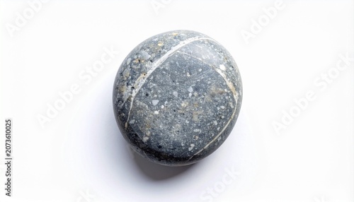 A close-up photo of a gray stone with white spots on a plain surface