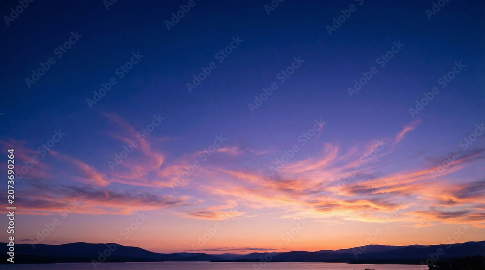 Fototapeta premium Deep Dusk Sky with Wispy Clouds Over Horizon and Water