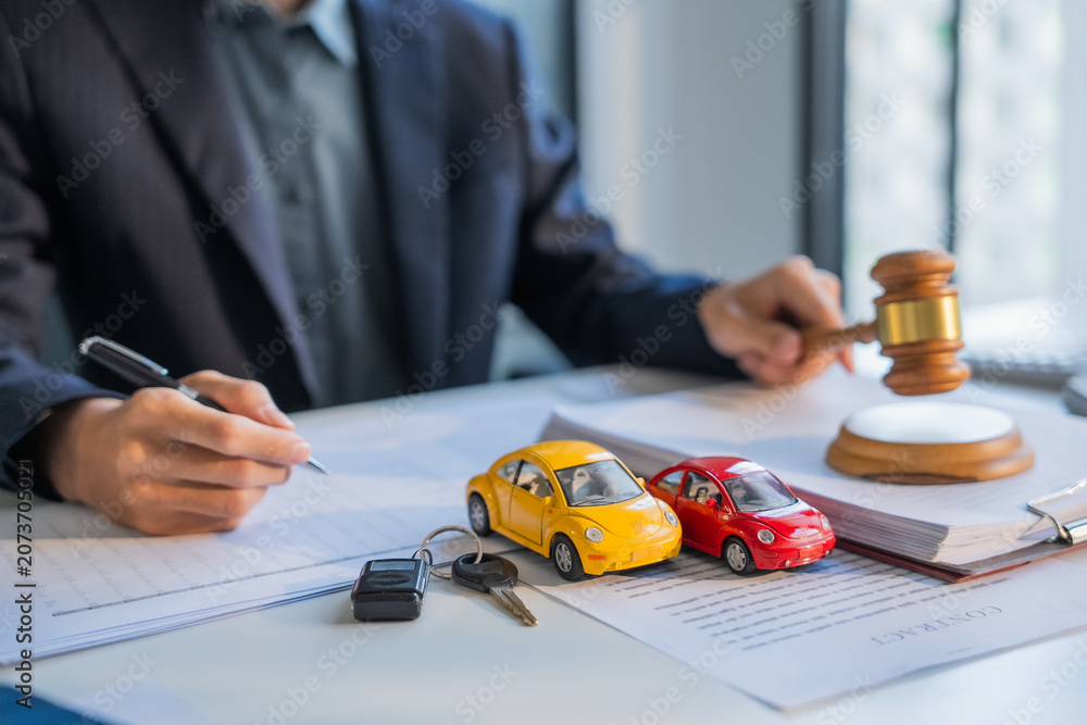 Fototapeta premium Lawyer writing on document and knocking gavel car insurance concept