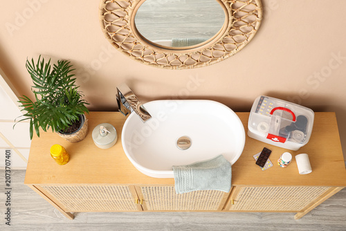 Cuadro en lienzo Bathroom sink with first aid kit and toiletries on wooden cabinet