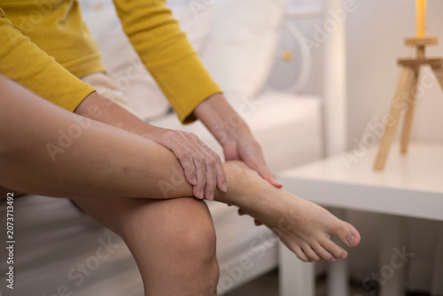 The woman clutched her foot in pain, which may indicate injury, inflammation, or arthritis. This is a health concern and should be considered.