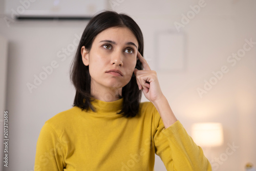 The young woman was deep in thought about something in the bedroom, her posture showing contemplation and worry.