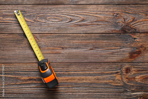 Obraz na plátně Measuring tape extended on wooden surface