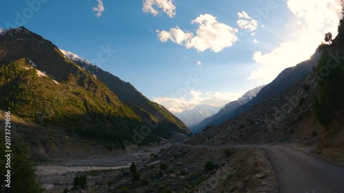 4K POV shot of a vehicle moving on a rural dirt road in front of the snow covered Himalayan mountain ranges during the sunset at Miyar Valley in Lahaul and Spiti district, Himachal Pradesh, India.