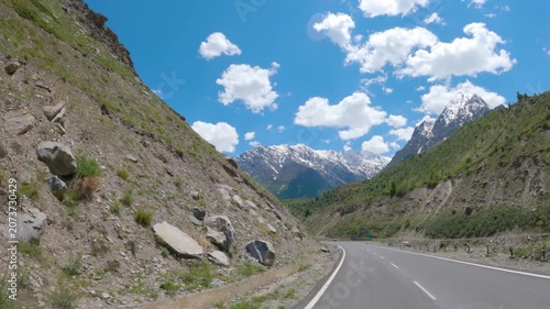 4K POV shot of a vehicle moving on a highway in front of snowy Himalayan mountain peaks during the summer season as seen near Keylong in Lahaul and Spiti district, Himachal Pradesh, India. 