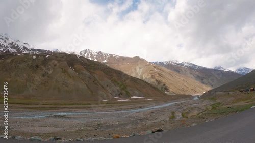 4K Scenic view of dry Himalayan mountain ranges with clouds above them and a small river flowing in the mountain valley as seen from Leh Manali highway on the way towards Ladakh. Scenic natural view.