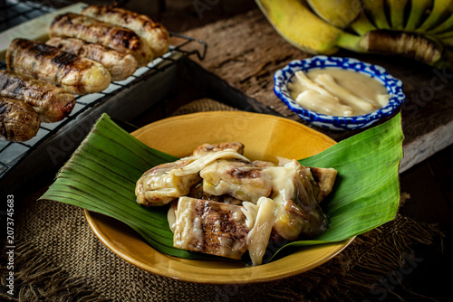 фотографія Traditional Thai grilled bananas with sweet coconut milk dipping sauce served on a plate with banana leaf, popular Asian street food dessert and sweet afternoon snack lifestyle concept