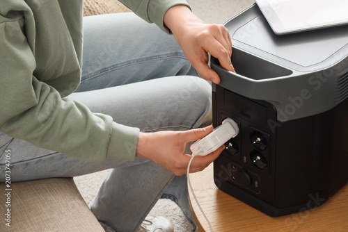 Obraz na płótnie Person plugging device into portable power station