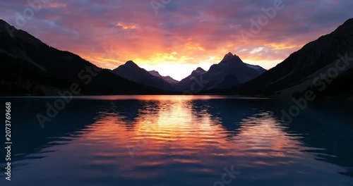 Stunning sunset over a tranquil lake surrounded by majestic mountains, reflecting vibrant colors