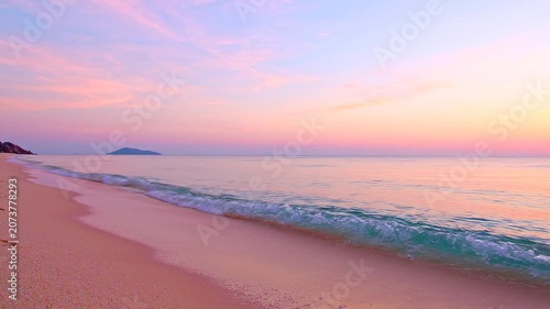 Stunning Pastel Sunset Over A Tranquil Tropical Beach Shoreline With Gentle Waves Rolling Onto The Sandy Coast At Dusk