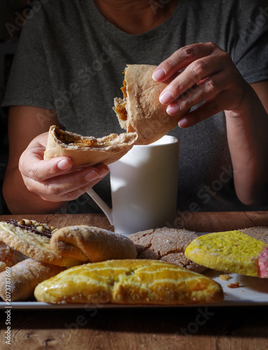 Hands holding food; traditional Mexican pastries and baked goods to enjoy with hot chocolate,coffee or milk. meal to get together with family, side view vertical