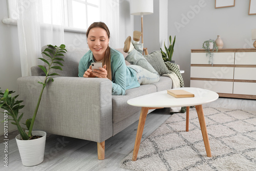 Smiling young woman using m...