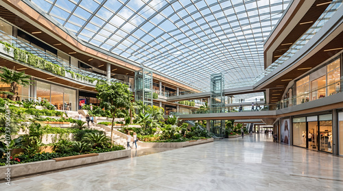 Modern shopping mall atrium with glass roof and plants