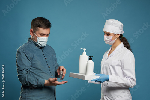 Fotografie doctor applying antibacterial spray on patient hands on blue background