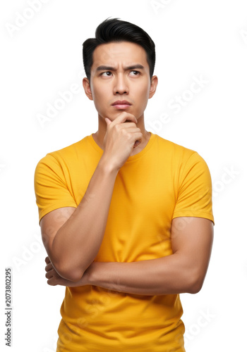 young east asian man in a vibrant marigold yellow t-shirt, hand on chin in pensive pose, isolated on a high-key white cyclorama studio background with copy space. concept of mental effort