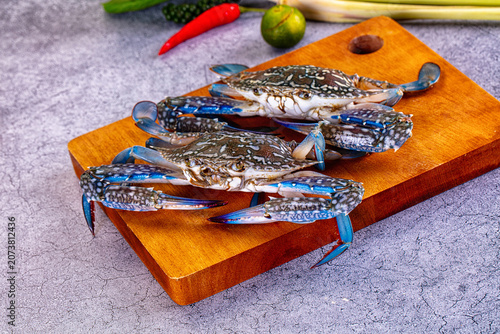 Fresh blue crabs on wooden cutting board with lime chili and lemongrass