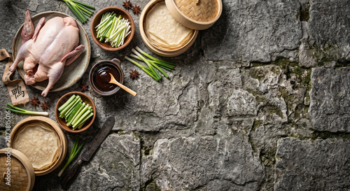 Cinematic overhead flat lay of Peking Duck ingredients on ancient stone wall