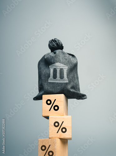Фотография Banking risk and interest rate risk concept featuring a bank asset symbol balanced on percentage blocks
