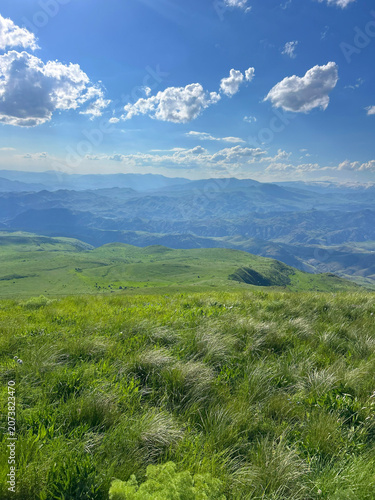 Panoramic Green Highland Valley with Mountains and Cloudy Sky