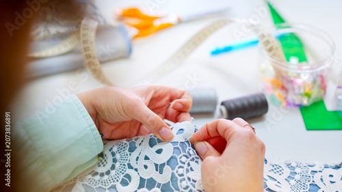 Konstfotografi Crafter hands sewing clothes with lace in workshop