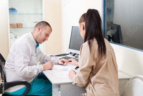 Quadro su tela Young male doctor examining and consulting young female patient in hospital clinic