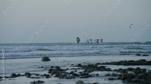 Kitesurfers riding ocean waves near shore in Jericoacoara Beach, Brazil.