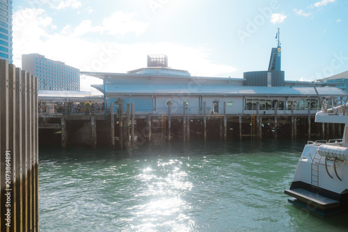 Auckland, New Zealand: waterfront view of Waitemata Harbour sea with historic wooden ferry terminal pier structures and white motor boat hull docked.