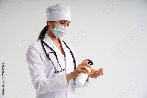 Photography doctor applying antibacterial spray on hand on white background