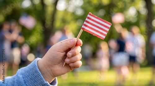 Young child holding small american flag during sunny outdoor celebration.