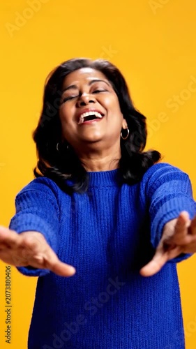 A happy mature woman smiles with her hands raised in joy