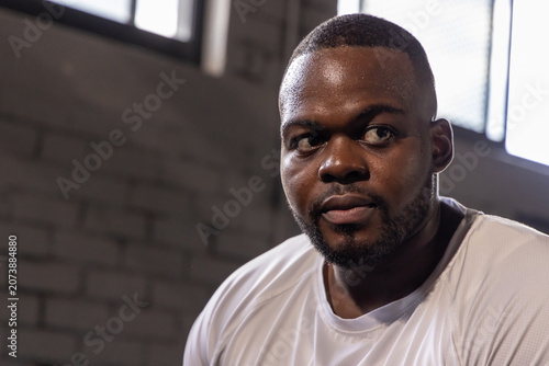 Photos Resting after intense training, man wearing white athletic T-shirt sweating in g
