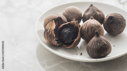 Black garlic on a small white plate. 