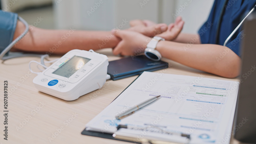 Fototapeta premium Digital blood pressure monitor used during a medical checkup, highlighting healthcare assessment, hypertension screening, patient monitoring, and preventive care.