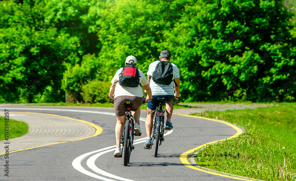 Fototapeta premium Cyclists ride on the bike path in the city Park 