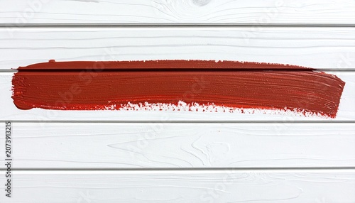 A bold red brush stroke across a white wooden background.