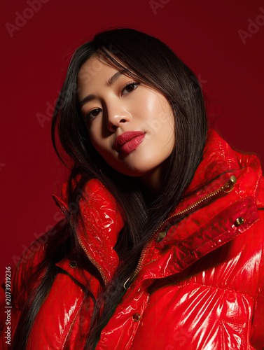 Asian Woman Fashion Portrait in Glossy Red Jacket on Red Background