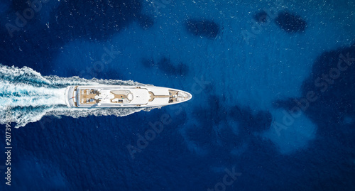Aerial overhead view of a modern luxury yacht sailing over the blue ocean with copy space