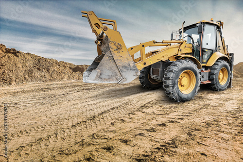 Photos Universal excavator loader digs into the ground at a construction location with